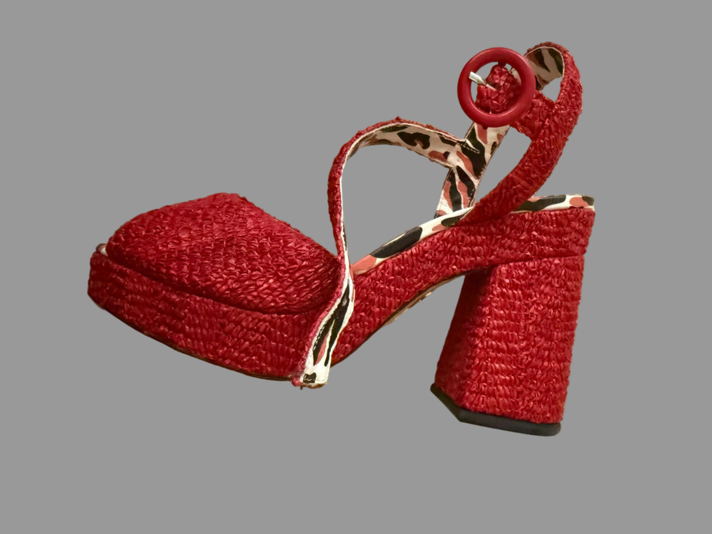 Red high-heeled shoe charm on a beige background