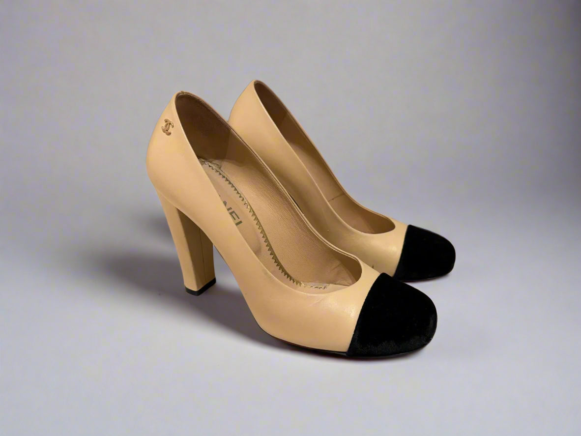 Side view of CHANEL Cap-Toe Two-Tone Pumps in size 38C. The shoes showcase a sleek profile with a black velvet cap-toe and beige leather upper.