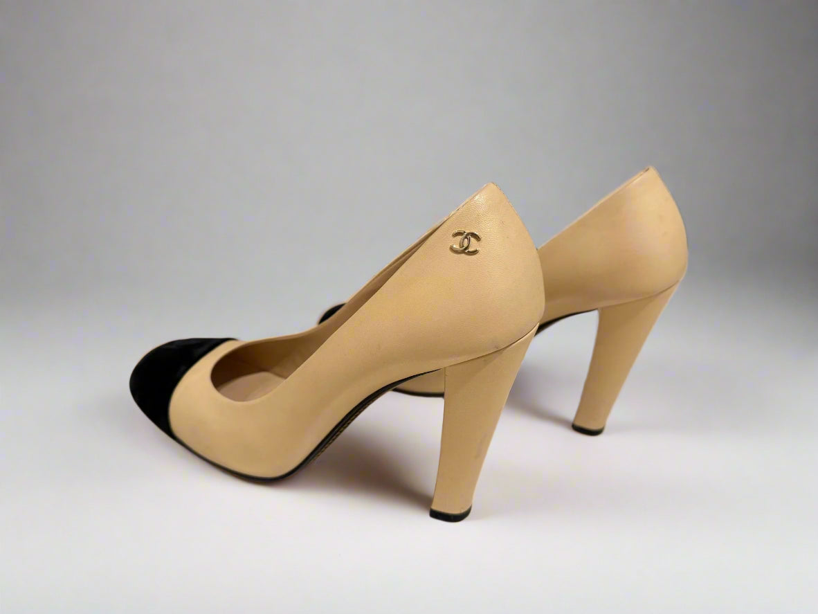 Side view of CHANEL Cap-Toe Two-Tone Pumps in size 38C. The shoes showcase a sleek profile with a black velvet cap-toe and beige leather upper.