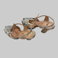 A pair of metallic silver Fendi sandals with cutout details and ankle straps.