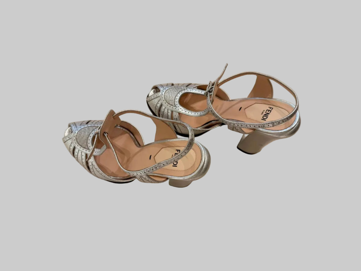 A pair of metallic silver Fendi sandals with cutout details and ankle straps.