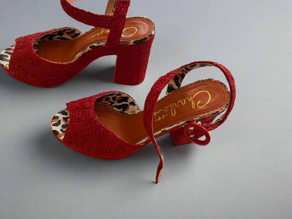 Red high-heeled shoes with leopard print insides on a light surface
