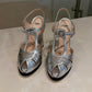 A pair of Fendi metallic silver peep-toe high heels with strappy T-strap details and rhinestone embellishments.
