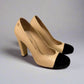 Side view of CHANEL Cap-Toe Two-Tone Pumps in size 38C. The shoes showcase a sleek profile with a black velvet cap-toe and beige leather upper. 