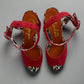 Red sandals with patterned straps on a light background