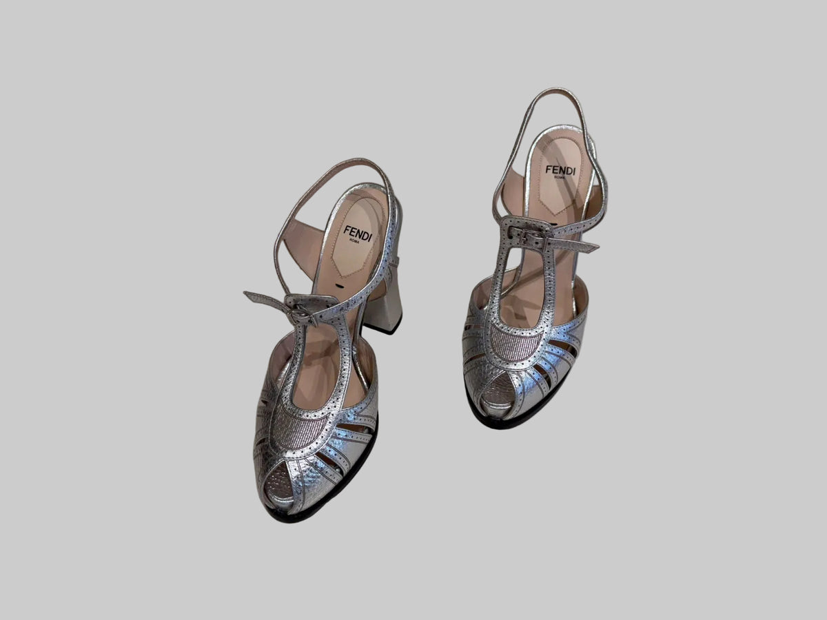 A pair of Fendi metallic silver slingback high heels with cutout detailing and T-strap bows.