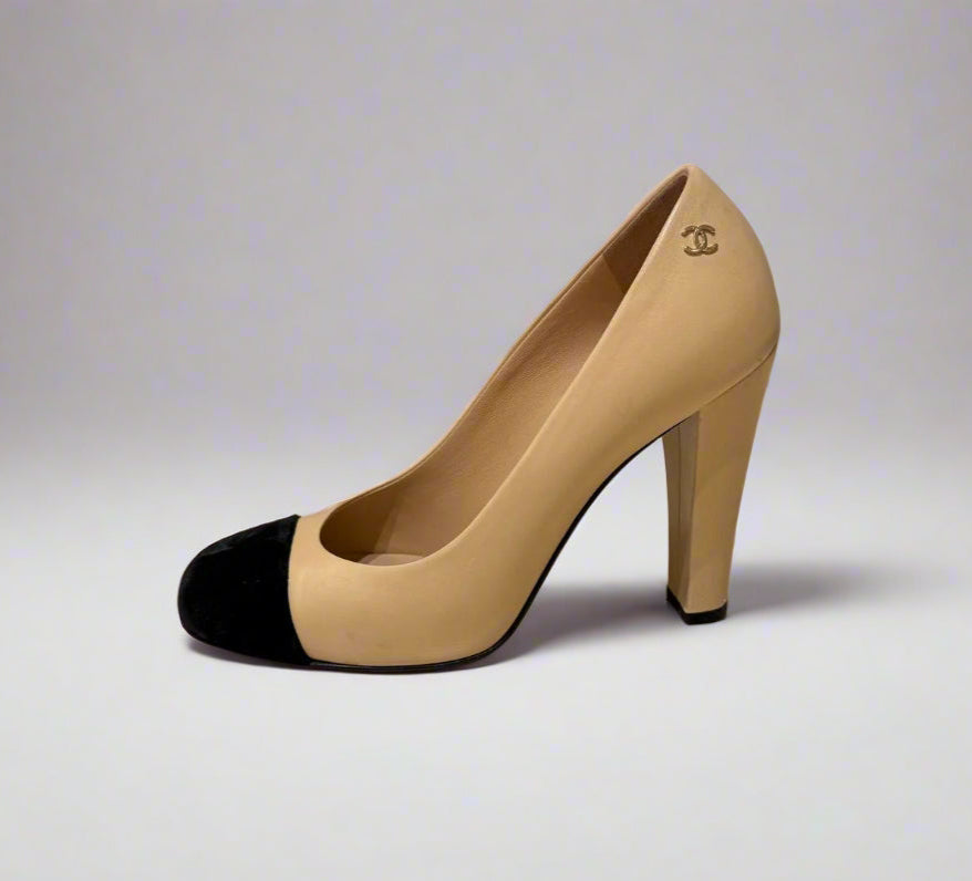 Side view of CHANEL Cap-Toe Two-Tone Pumps in size 38C. The shoes showcase a sleek profile with a black velvet cap-toe and beige leather upper.