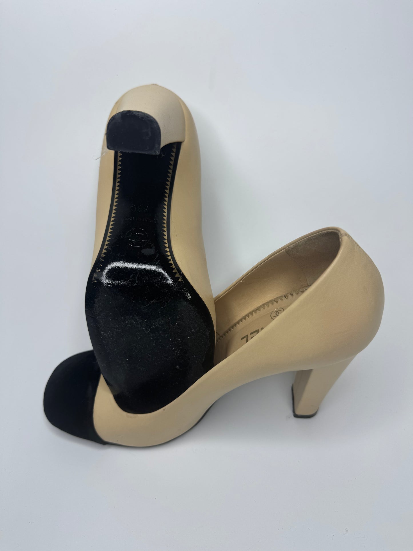 Close-up view of the heel and sole of CHANEL Cap-Toe Two-Tone Pumps in size 38C. The heel features a textured pattern for added grip, and the sole shows signs of minimal wear, indicating the shoes are in good condition