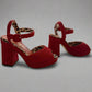 Red high-heeled shoes with leopard print details on a reflective surface.
