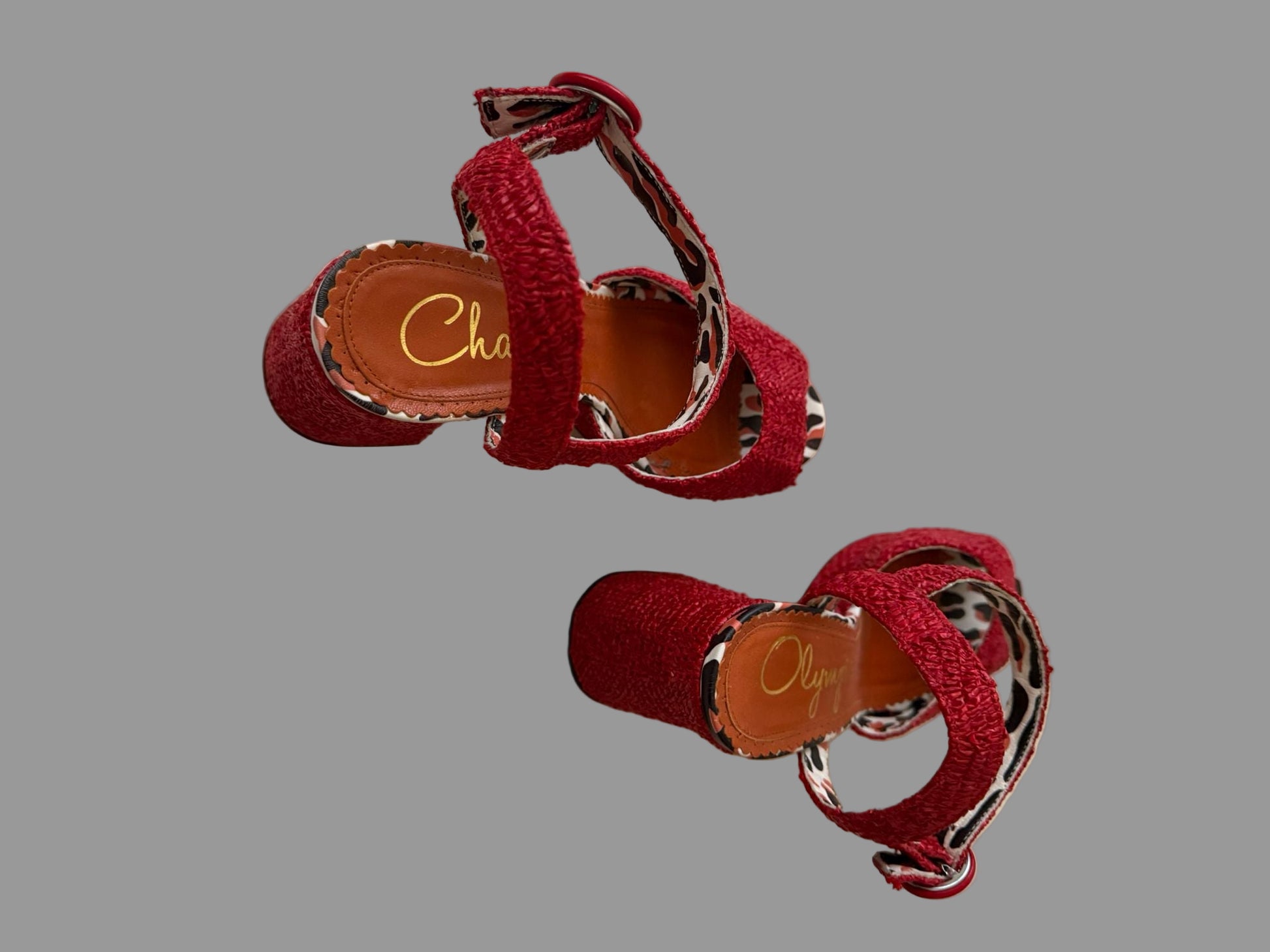 Red sandals with leopard print straps on a beige surface